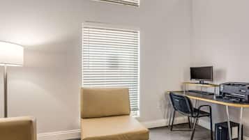 A room with a desk, computer, printer, and a chair.