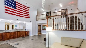 A hotel lobby with a reception desk, a flag, a staircase, and a sofa.