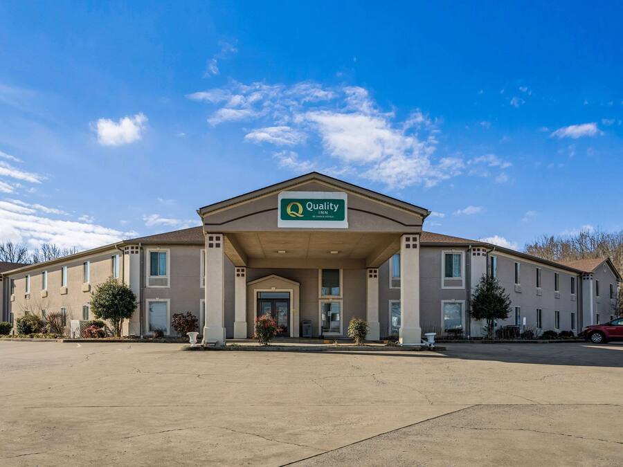 A Quality Inn hotel with a central entrance, a parking lot, and a clear blue sky.