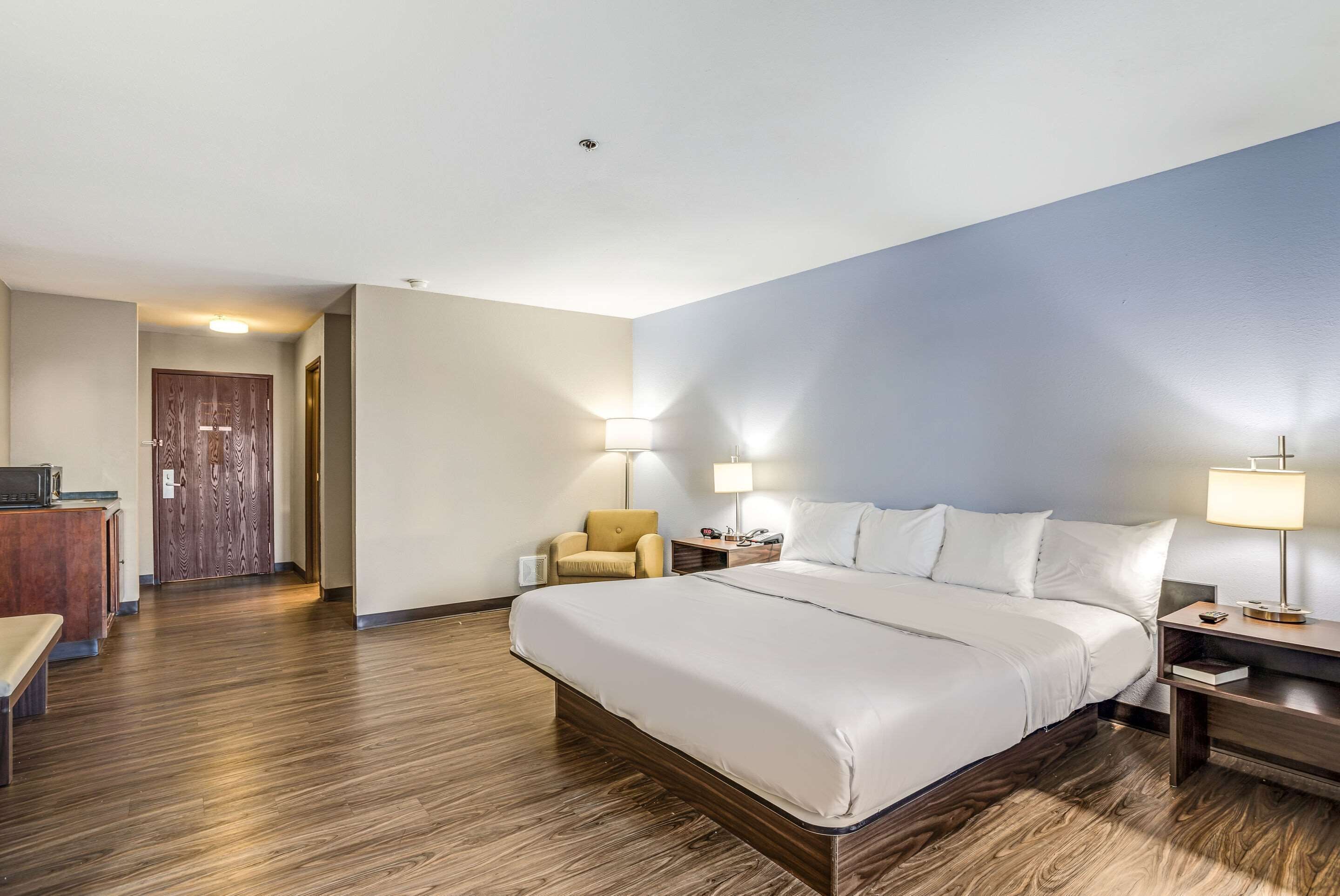 Una camera d'albergo con un letto grande, una scrivania con una sedia e due lampade ai lati del letto.