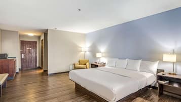 Una camera d'albergo con un letto grande, una scrivania con una sedia e due lampade ai lati del letto.