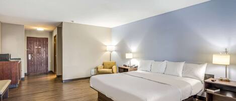 Una habitación de hotel con una cama grande, un escritorio con una silla y dos lámparas de noche.