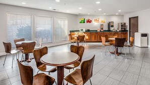 A modern kitchen with a central island, bar area, and dining space with round tables and chairs.