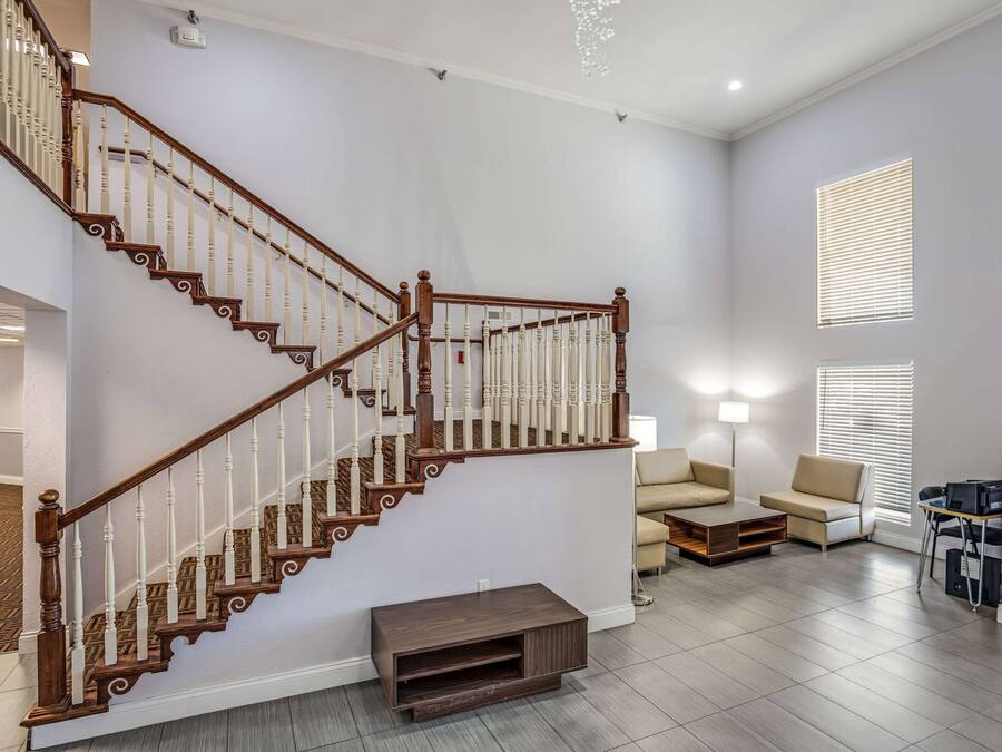 Un salon moderne avec un escalier en bois, un canapé, une table basse et un meuble pour la télévision.