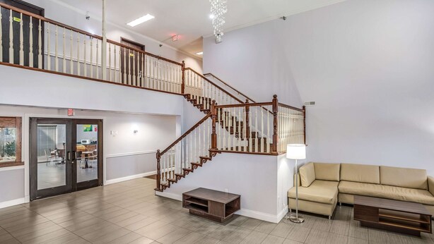 A spacious lobby with a wooden staircase, a sofa, and a TV stand.