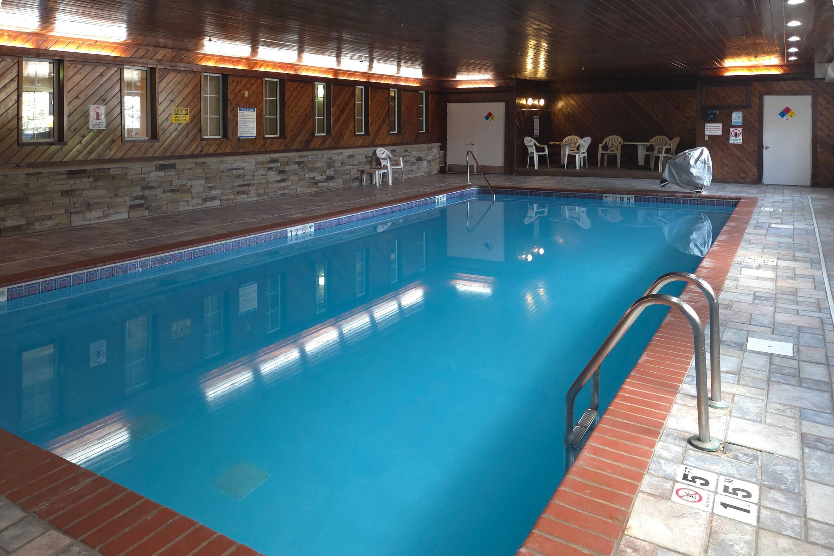 An indoor swimming pool with wooden walls, tiled floor, and a lifeguard stand.