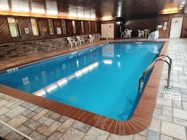 Una piscina interior con pared de madera y suelo de baldosas.