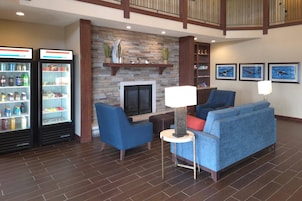 Un hall con chimenea de piedra, asientos azules y un refrigerador lleno de bebidas.