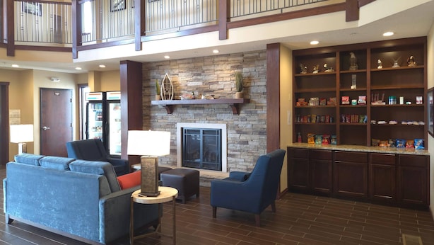 A lobby with a stone fireplace, seating area, and a snack bar with shelves. - MainStay Suites LeClaire - Quad Cities (Le Claire)
