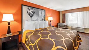 A hotel room with a large bed, two bedside tables with lamps, a chair, a window with curtains, and a framed picture on the wall. - Super 8 by Wyndham Marana/Tucson Area (Tucson)