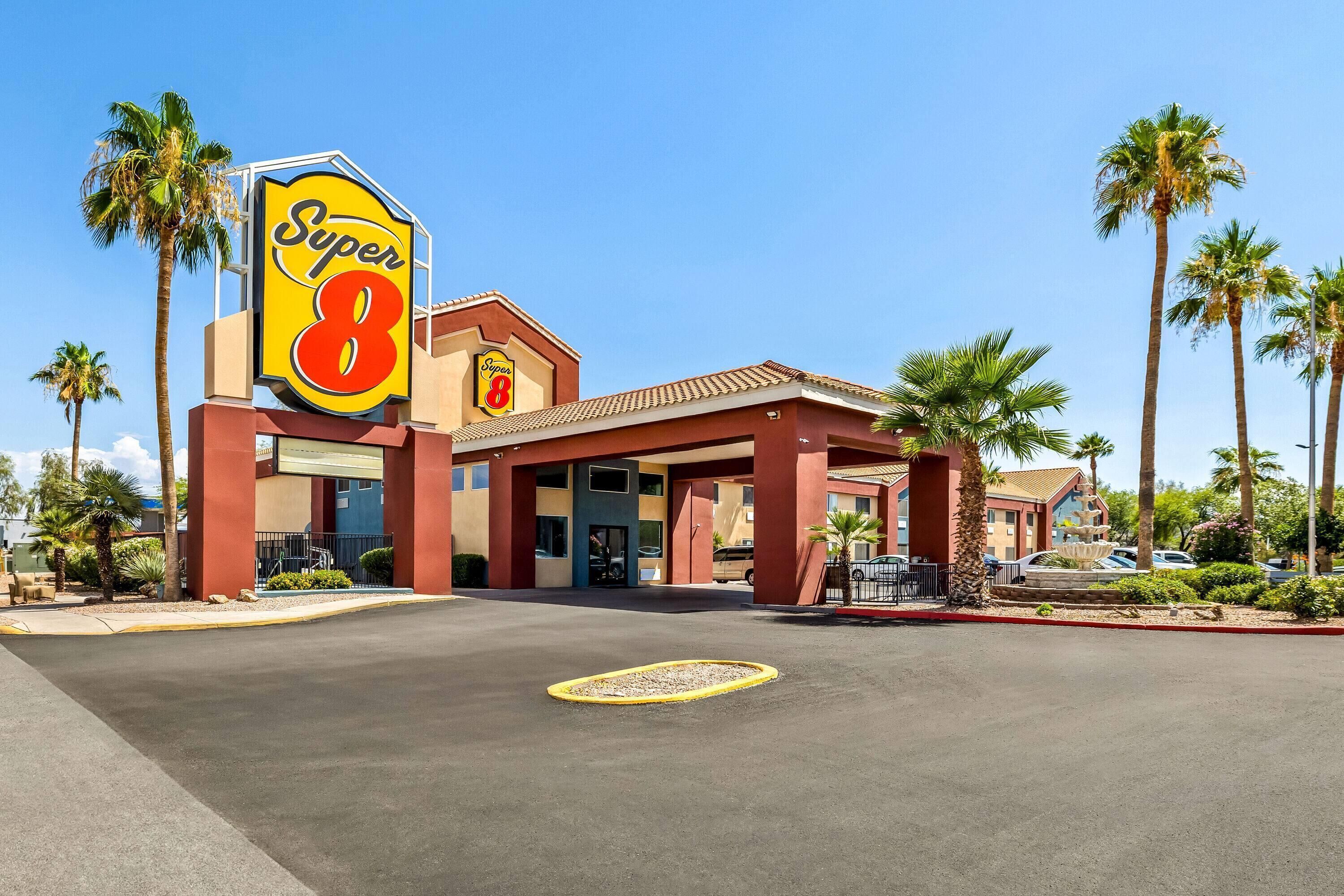 A Super 8 hotel with a prominent sign, palm trees, and a clear blue sky.