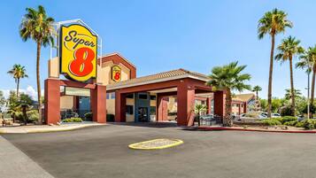 A Super 8 hotel with a prominent sign, palm trees, and a clear blue sky.