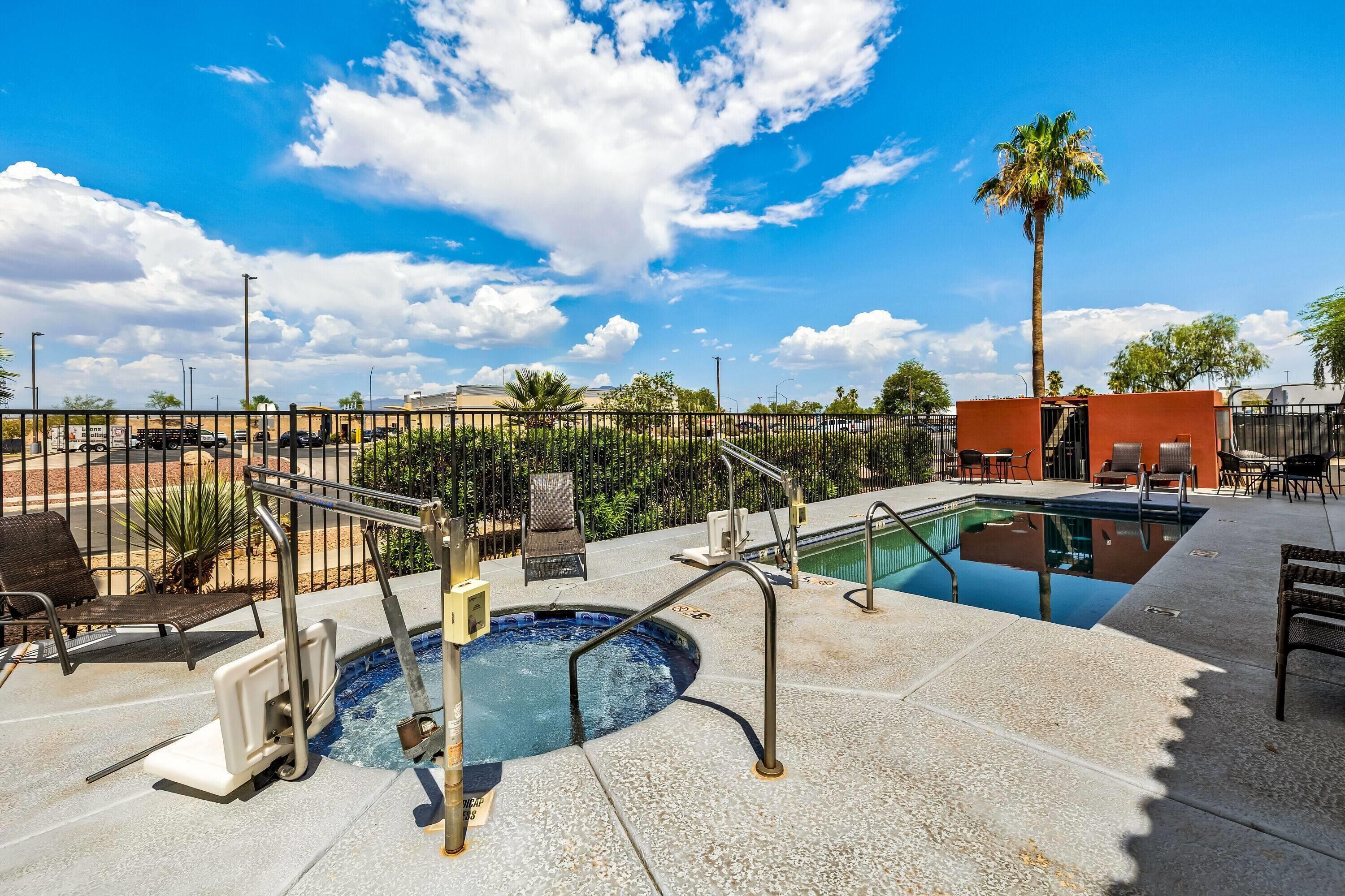 A rooftop pool area with a hot tub, lounge chairs, and a palm tree.
