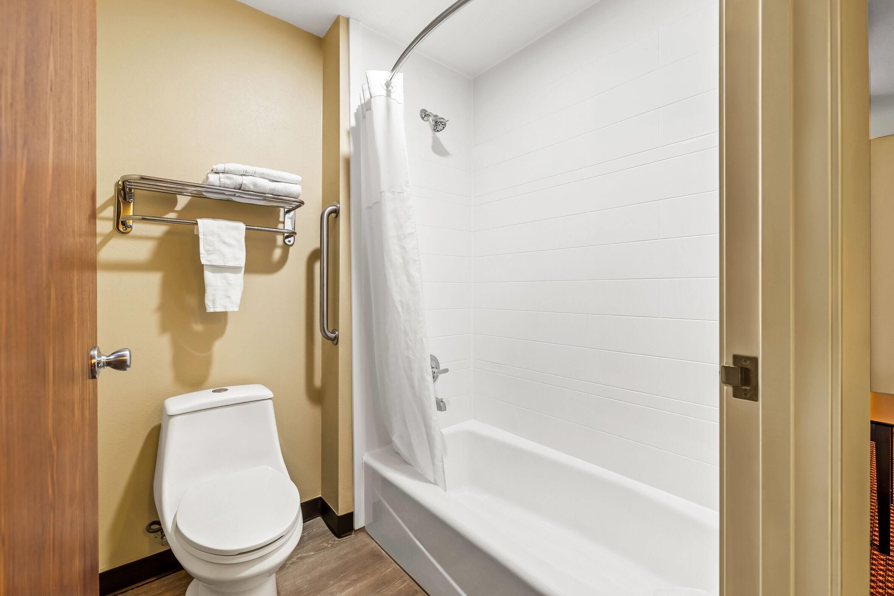 A bathroom with a toilet, a bathtub with a shower curtain, and a towel rack.