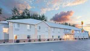 Un motel con techo plano, numerosas ventanas y aparcamiento.