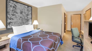 Ein Hotelzimmer mit einem großen Bett, zwei Nachttischen, einem Schreibtisch mit Stuhl, einem Fernseher und einer Tür zu einem weiteren Raum.