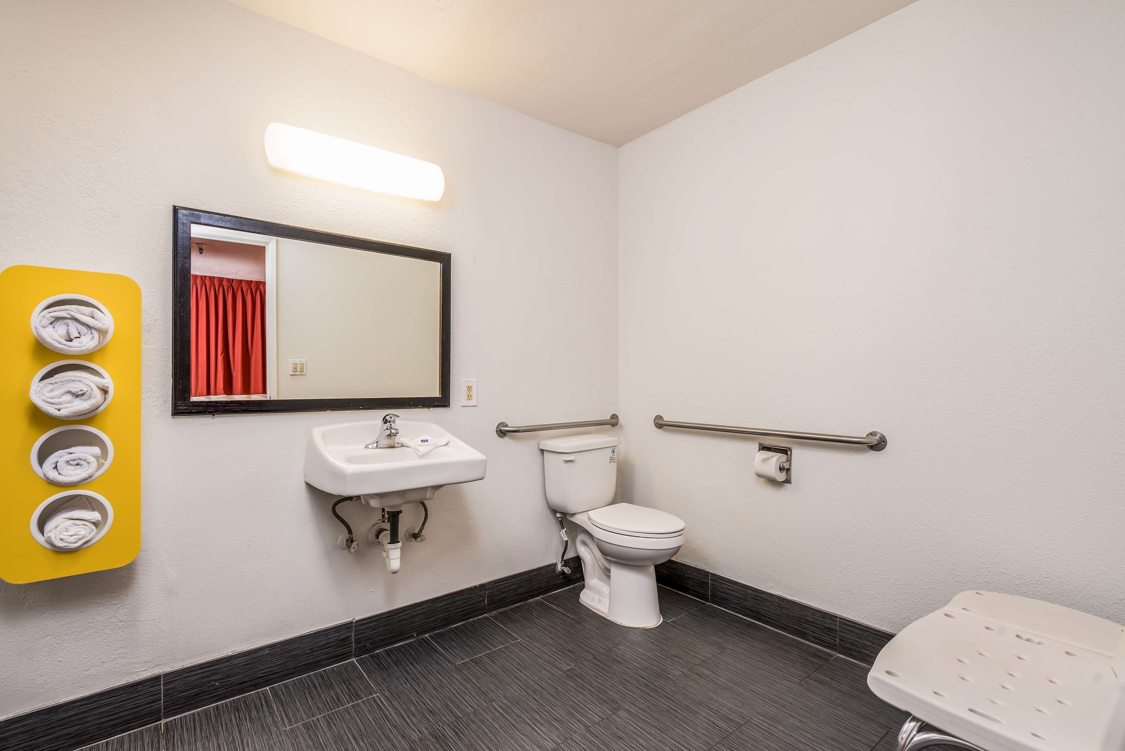 A bathroom with a white sink, toilet, and a yellow towel rack.
