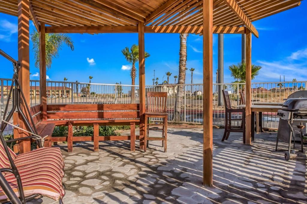A covered outdoor seating area with a wooden bench, a dining table, and a grill.