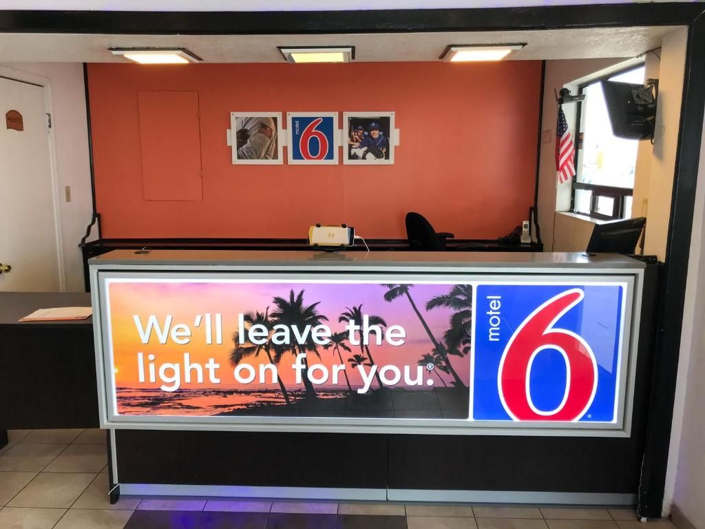 A motel reception desk with a large sign stating 'We'll leave the light on for you.'