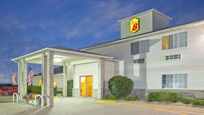 A hotel with a prominent '8' sign, a covered entrance, and American flags. - Super 8 by Wyndham Clarinda (Clarinda)