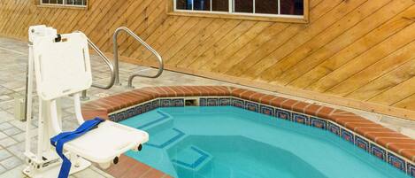 An indoor swimming pool with a wooden wall and a tiled edge.