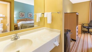 A hotel bathroom with a large sink, mirror, and towel rack. - Super 8 by Wyndham Clarinda (Clarinda)