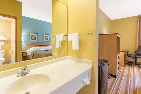 A hotel bathroom with a large sink, mirror, and towel rack.