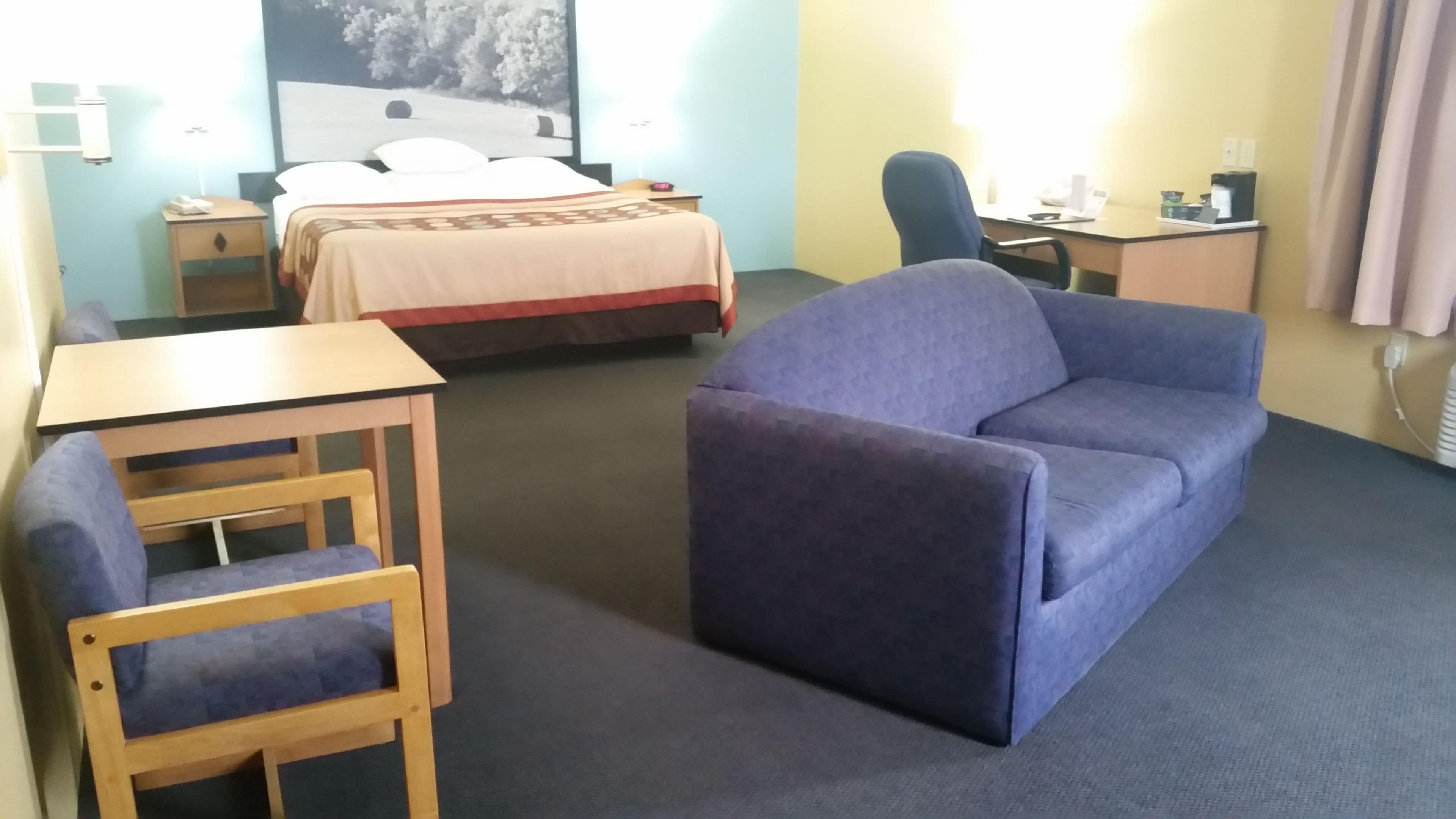 A hotel room with a bed, a desk, a chair, and a sofa.
