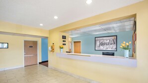 A reception area with a reception desk, a framed cityscape poster, and a potted plant. - Super 8 by Wyndham Clarinda (Clarinda)