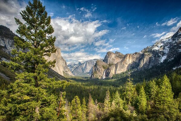 A mountainous landscape with a prominent waterfall, dense forest, and rocky cliffs. - Days Inn by Wyndham Yosemite Area (Fresno)