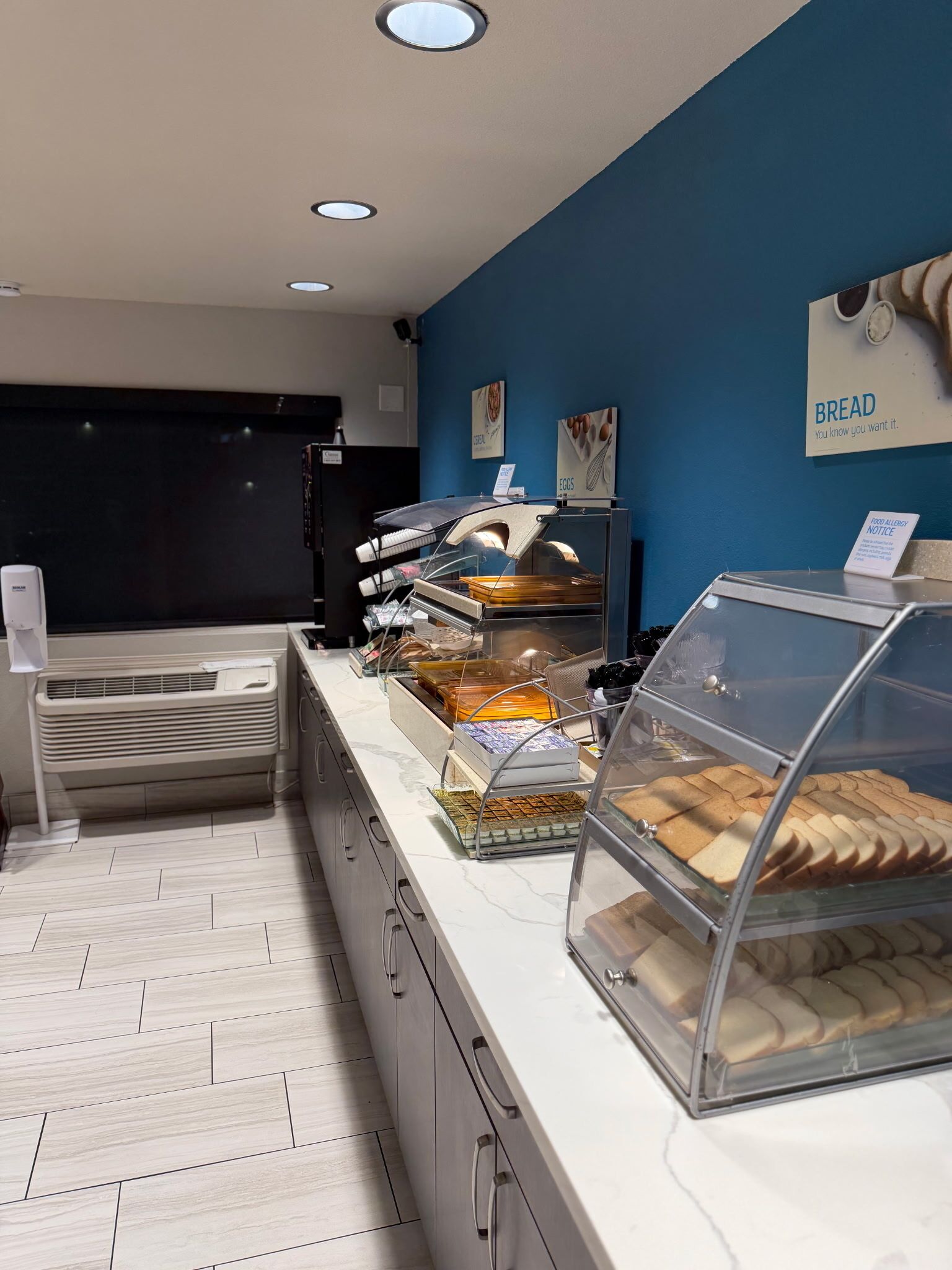 Mostrador de panadería con diversos productos horneados y un letrero que indica una advertencia sobre alérgenos alimentarios.