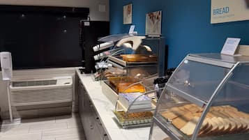Mostrador de panadería con diversos productos horneados y un letrero que indica una advertencia sobre alérgenos alimentarios.