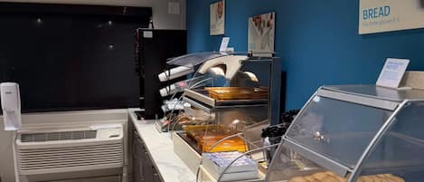 A bakery counter with various baked goods and a sign indicating a food allergy notice.