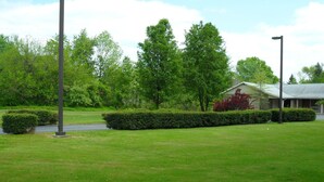 A grassy area with a building that has a stone facade and a sloped roof. - Red Carpet Inn (Gloucester City)