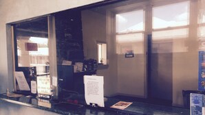 A reception desk with a glass partition, a "Check Out Time 11:00 AM" sign, a "Non-Smoking Room Available" sign, and a "Taxi" sign. - Red Carpet Inn (Gloucester City)