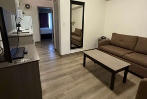 Un espacio habitable compacto con kitchenette, un sofá, una mesa de centro y un espejo.