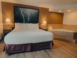 Una habitación de hotel moderna con una cama grande, dos lámparas de noche, un cabecero con diseño de rayo, suelo de madera y una bañera.