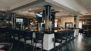 A modern bar area with a high counter, multiple bar stools, and a television screen.