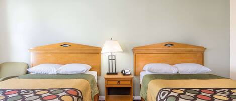 A hotel room with two beds, each with a wooden headboard, a nightstand with a lamp, and a telephone.