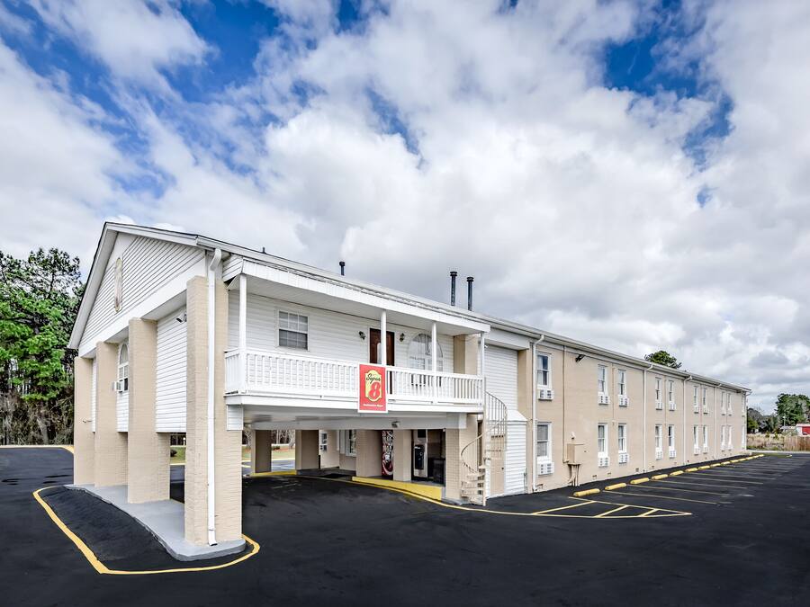 Un hotel con techo plano, balcón y estacionamiento.