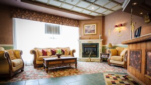 A traditional living room with a fireplace, two armchairs, a sofa, and a patterned rug. - Peterborough Inn & Suites Hotel (Peterborough)
