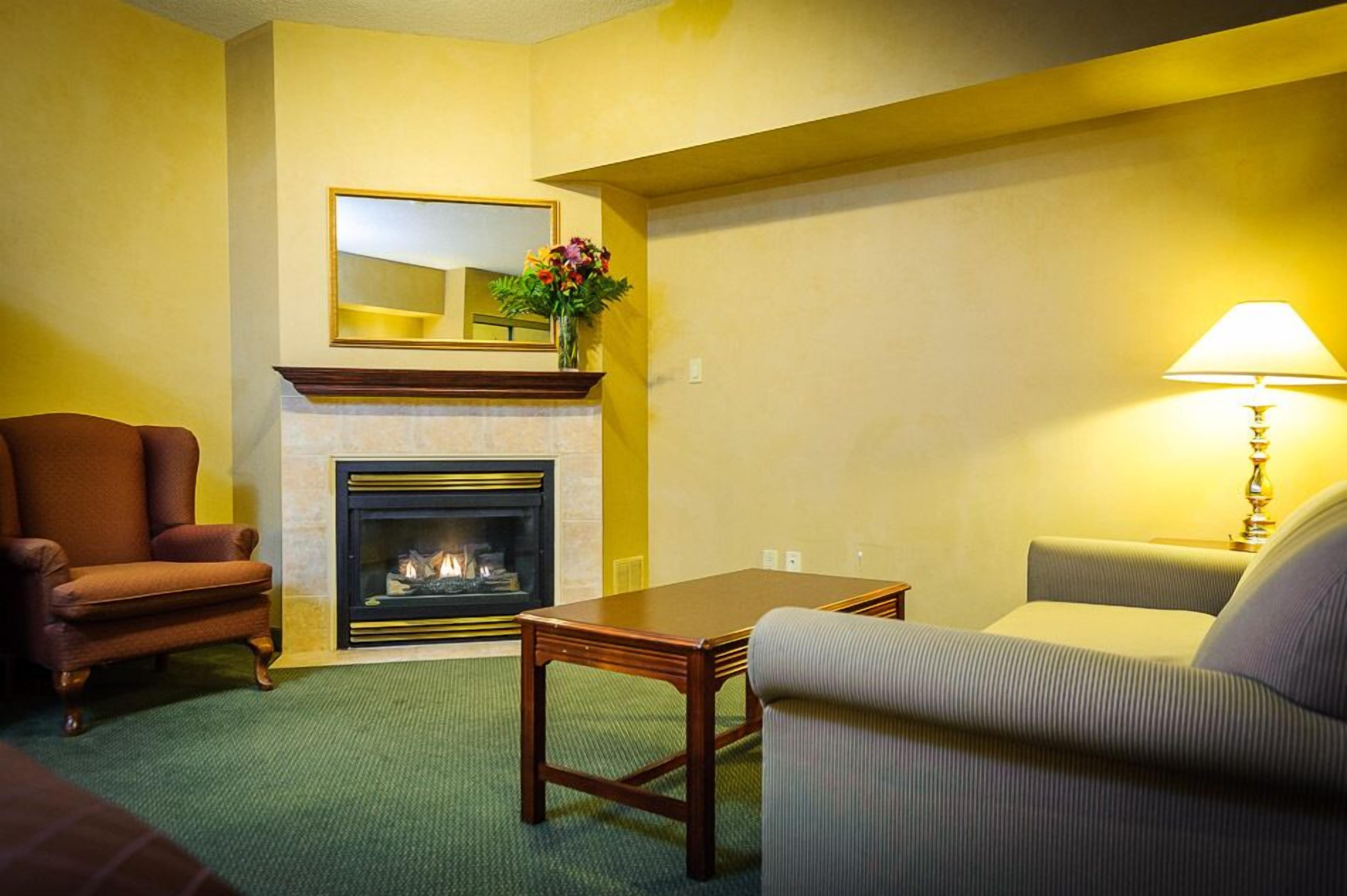 Ein gemütliches Wohnzimmer mit Kamin, Sofa, Sessel und Tisch.