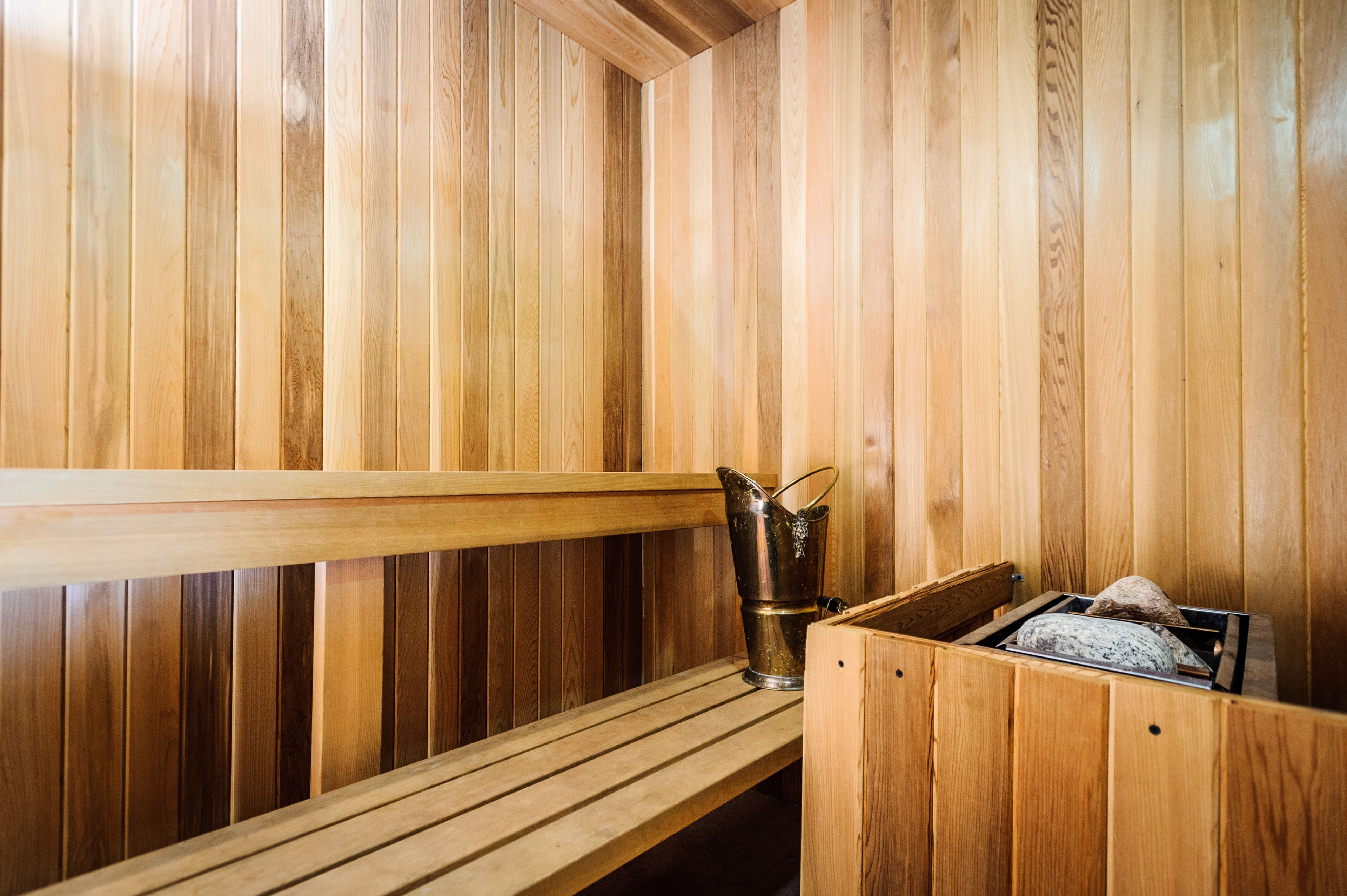 A wooden sauna with benches and a bucket.