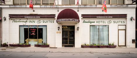 A hotel with a maroon awning, a sign indicating vacancies, and multiple flags.