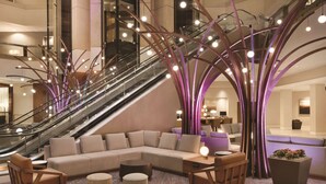 A modern lobby with a central seating area, an escalator, and a staircase. - Hyatt Regency Louisville (Louisville)