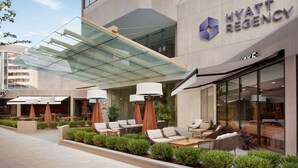 A modern hotel exterior with outdoor seating, a glass canopy, and a visible sign for the Hyatt Regency. - Hyatt Regency Louisville (Louisville)