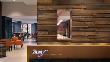 Ett entréområde med en väggpanel av trä och en neonskylt med texten ”Sway LOCAL SOUTHERN EATERY”.