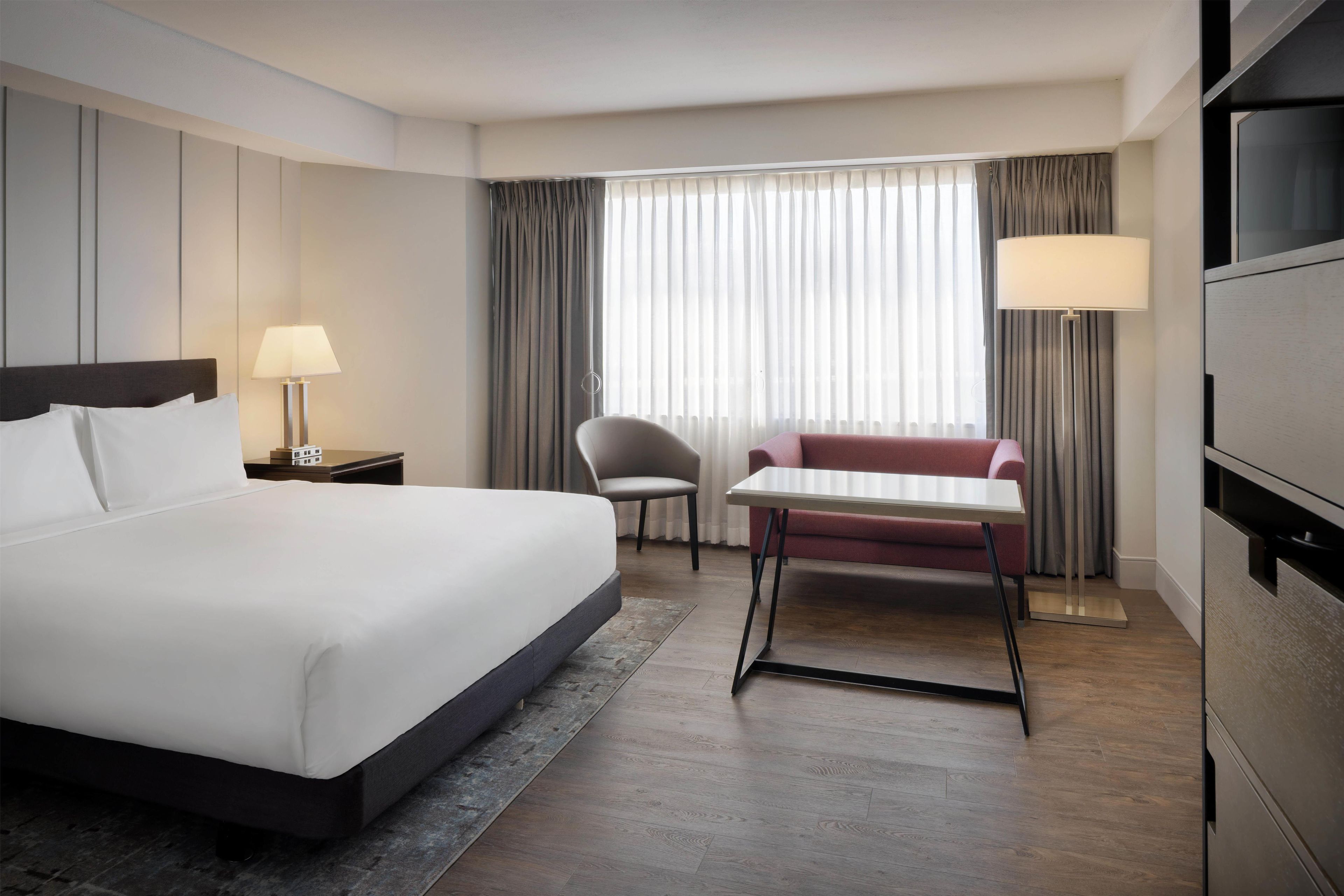 Une chambre d’hôtel avec un grand lit, un bureau, une chaise, un canapé et une télévision.