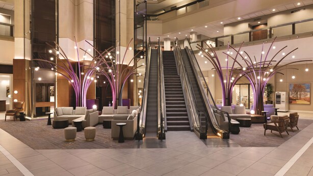 A spacious lobby with a central escalator, comfortable seating areas, and modern lighting fixtures. - Hyatt Regency Louisville (Louisville)