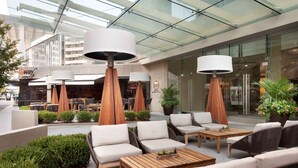 An outdoor seating area with wicker furniture, wooden tables, and large lamps. - Hyatt Regency Louisville (Louisville)